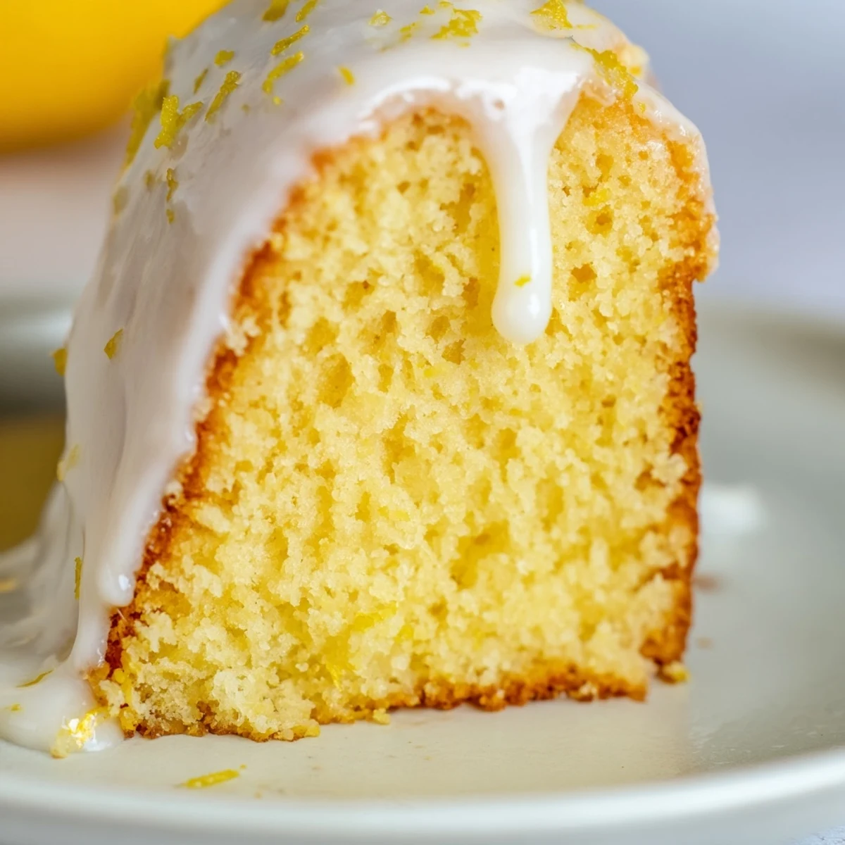 A lemon cake slice garnished with fresh berries and a cup of Earl Grey tea on a rustic table.