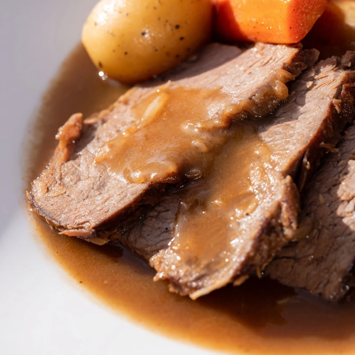 Tender Slow Cooker Roast Beef shredded on a platter with roasted veggies and a ladle of pan gravy.