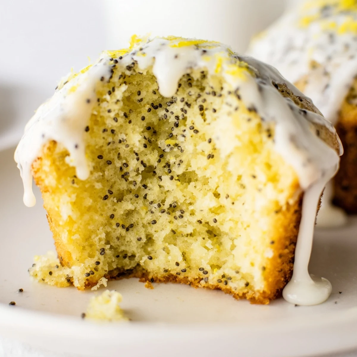 Morning sunlight highlights the fluffy texture of Lemon Poppy Seed Muffins with Yogurt alongside a steaming cup of black coffee.
