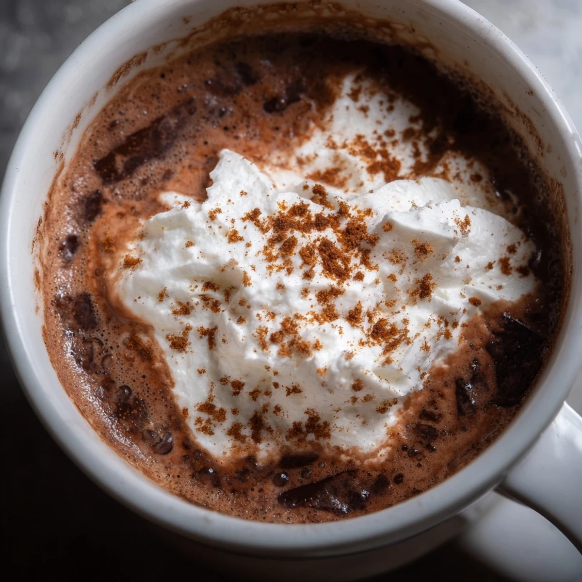 Cozy Spiced Hot Chocolate with Whipped Topping served beside cinnamon sticks for dipping.