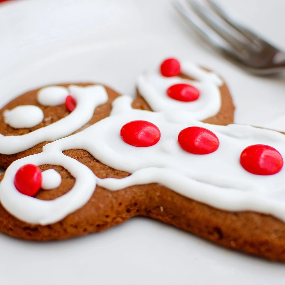 Freshly baked Gingerbread Baking with Kids cookies rest on a wire rack with scattered cinnamon sticks.