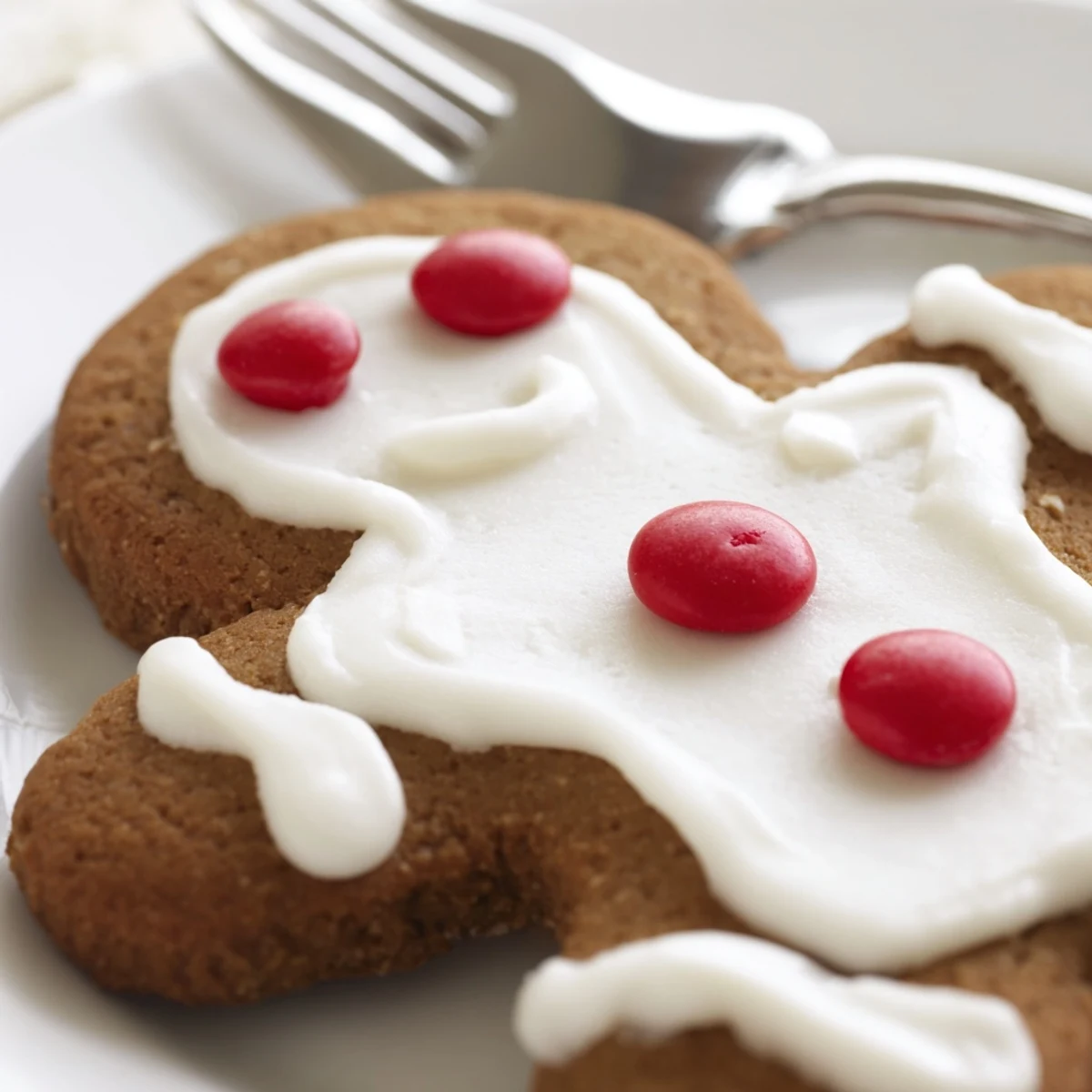 A child’s hand reaches for decorated Gingerbread Baking with Kids cookies beside colorful sprinkles and icing.