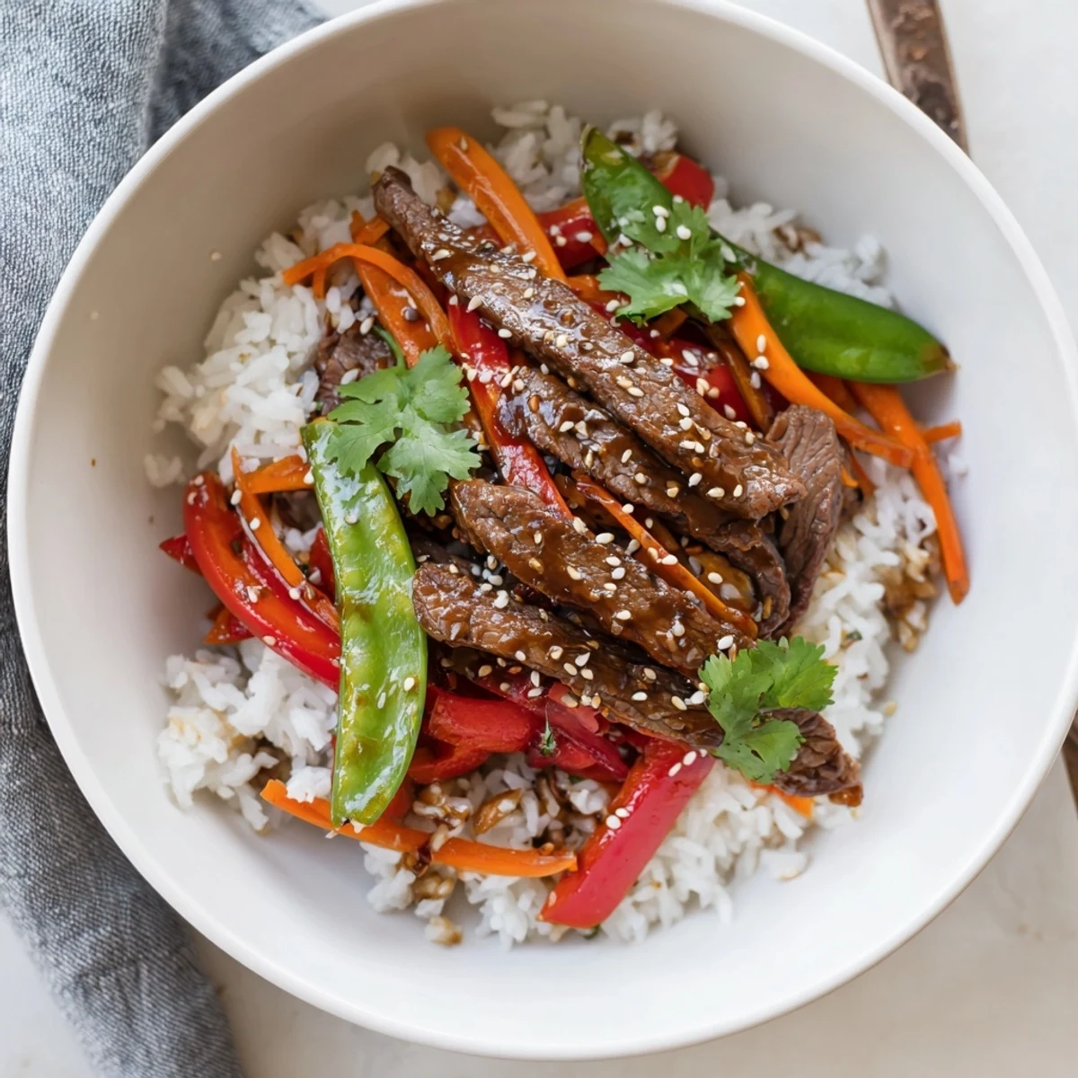 Close-up of a vibrant Beef Lunch Bowl with colorful vegetables and glistening sauce over fluffy rice.