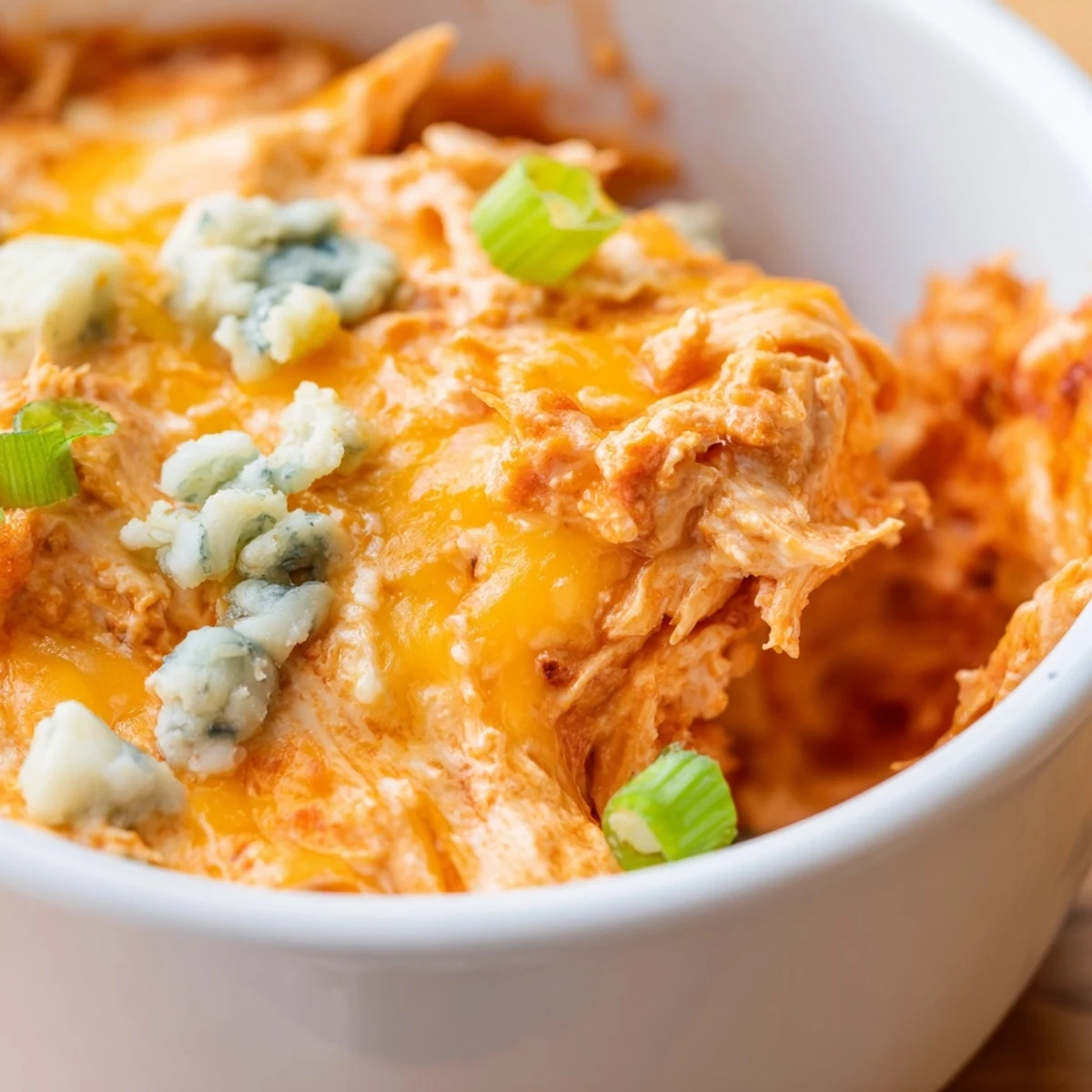 Golden, bubbly Spicy Buffalo Chicken Dip in a baking dish, garnished with green onions and served with crisp celery sticks and sturdy tortilla chips for dipping.