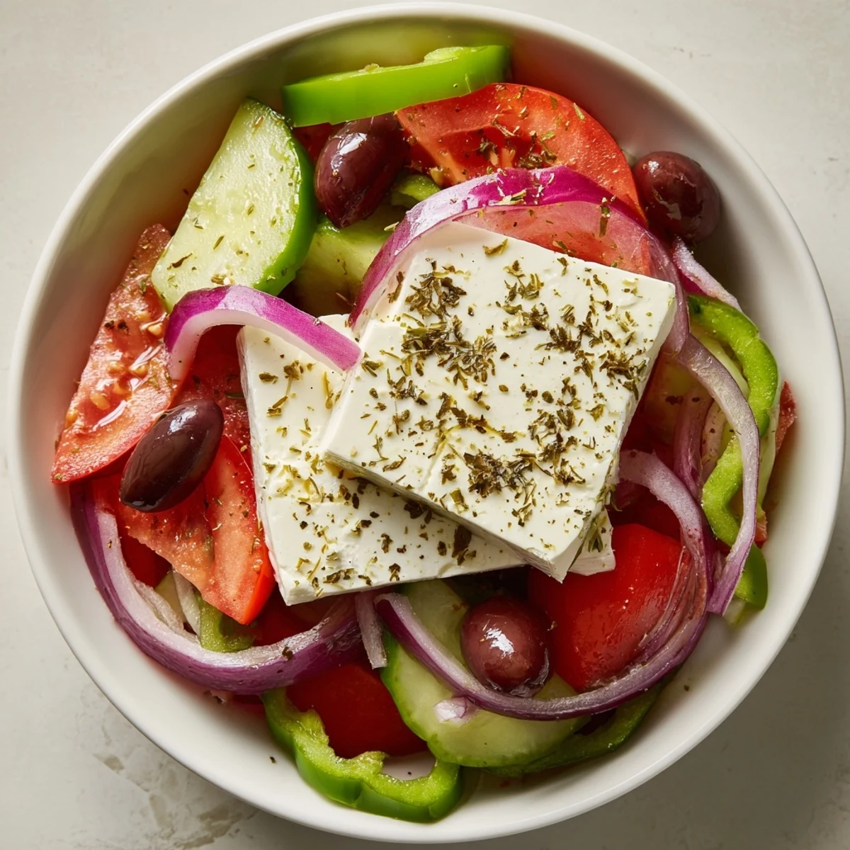 Vibrant Greek Salad with Kalamata olives, cucumbers, tomatoes, red onion, and creamy feta cheese, ready to serve with a light dressing.