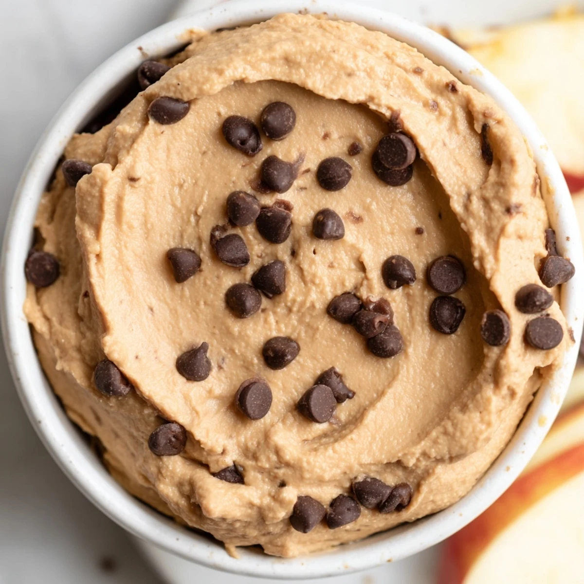 Vegan Chocolate Chip Cookie Dough Hummus dip topped with mini chocolate chips and fresh apple wedges for sharing.