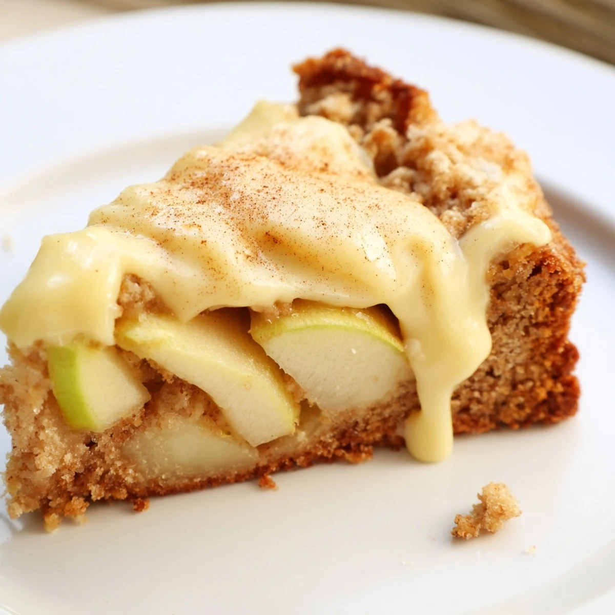 Freshly baked Irish Apple Cake with Custard Sauce on a rustic plate, topped with tender apple slices and a dollop of sauce.