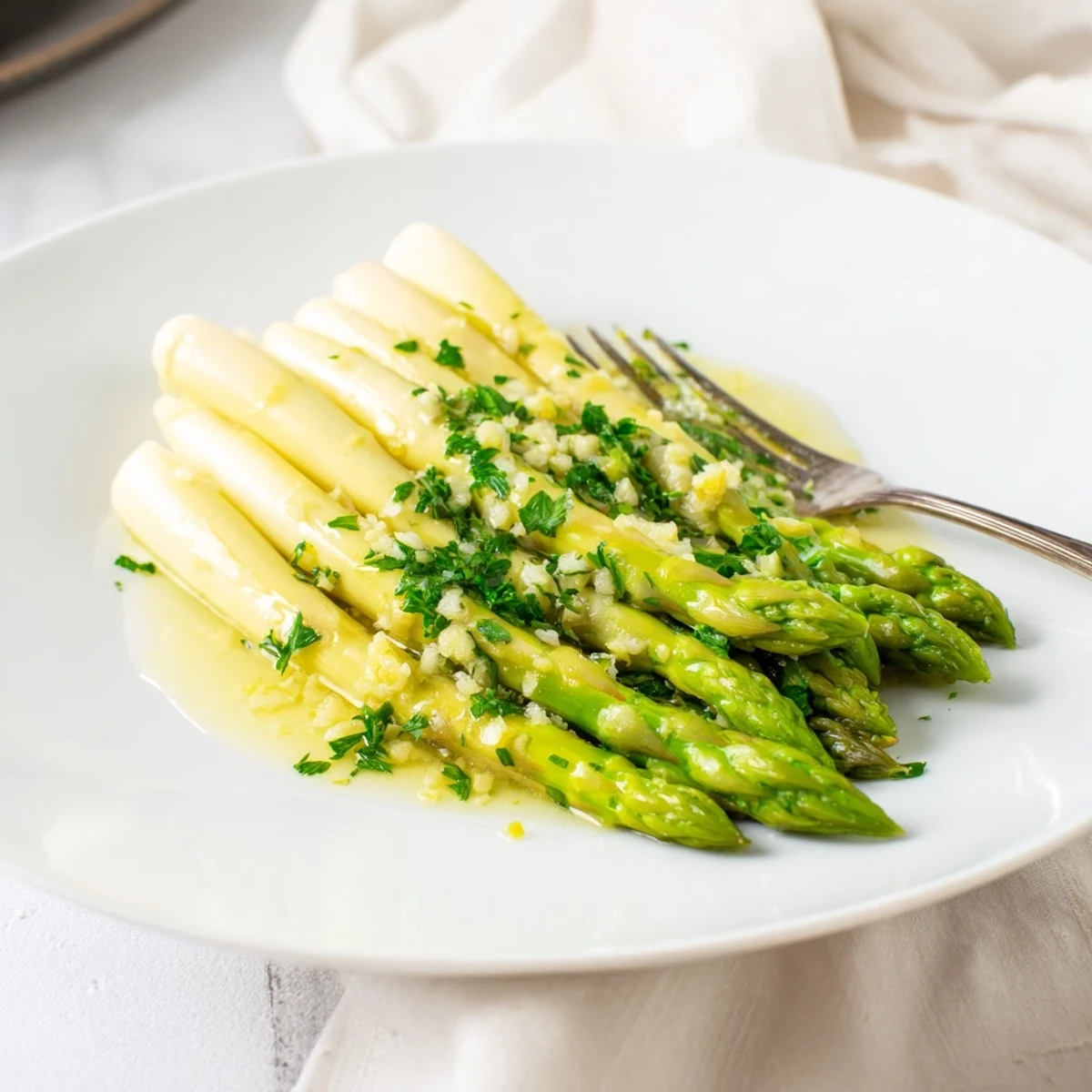 Bright green Lemon Garlic Asparagus with Butter sizzling in a skillet, garnished with fresh parsley and lemon zest.  
