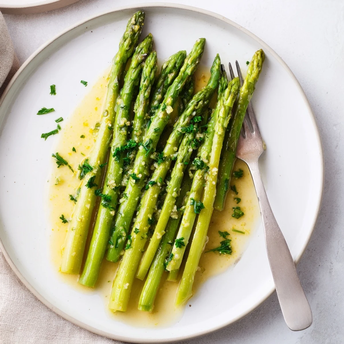 Tender asparagus spears coated in butter, garlic, and lemon juice, served as a vibrant vegetarian side dish.  