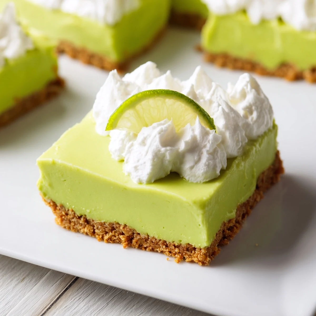 Vibrant green St. Patrick's Day Key Lime Pie Bars with a buttery graham cracker crust and fluffy whipped cream topping.