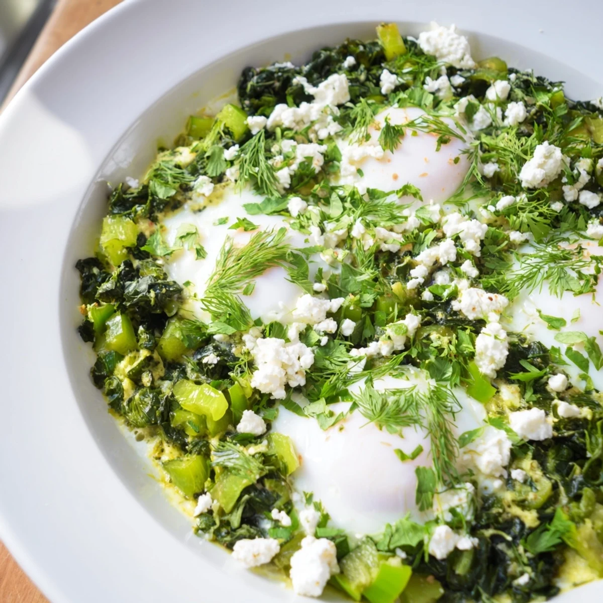 A healthy shakshuka with spinach and feta, showcasing colorful vegetables and fresh herbs, with eggs poached to runny perfection in a sizzling skillet.