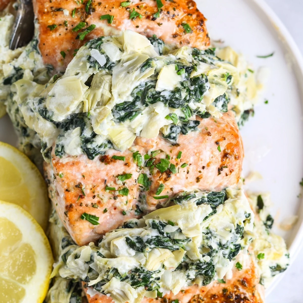 Close-up of Creamy Spinach and Artichoke Stuffed Salmon revealing a cheesy spinach filling baked inside tender salmon, highlighting the flaky texture and vibrant green colors.