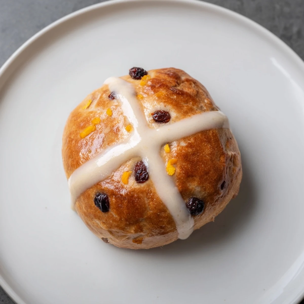 Golden brown Hot Cross Buns with currants and spices rest on a wire cooling rack after baking.