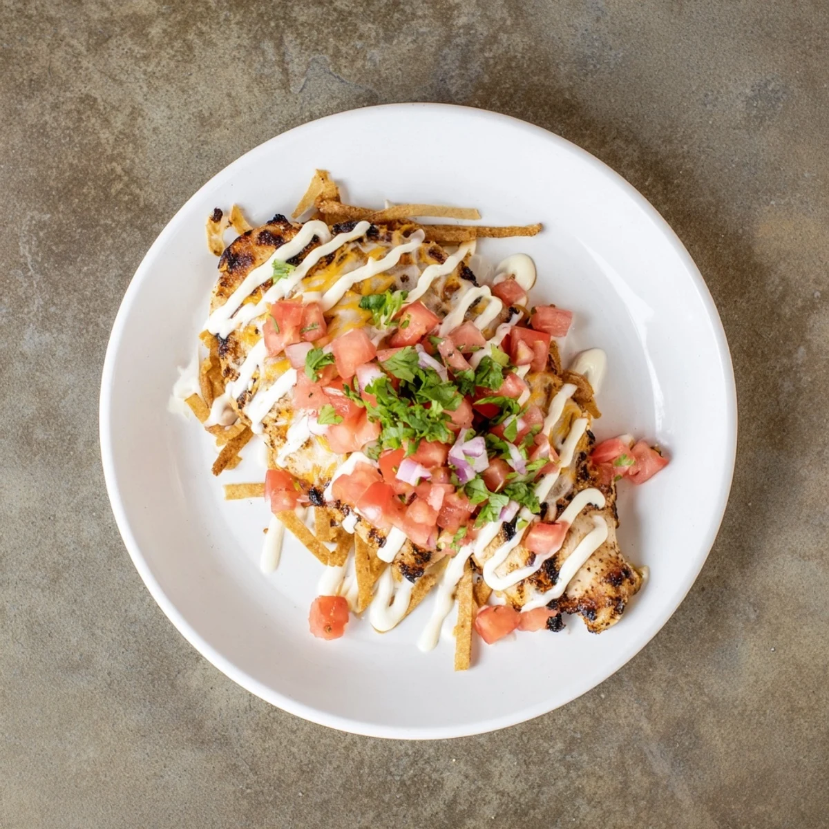 A close-up of bubbly Fiesta Lime Chicken broiled with cheese and served with lime wedges.