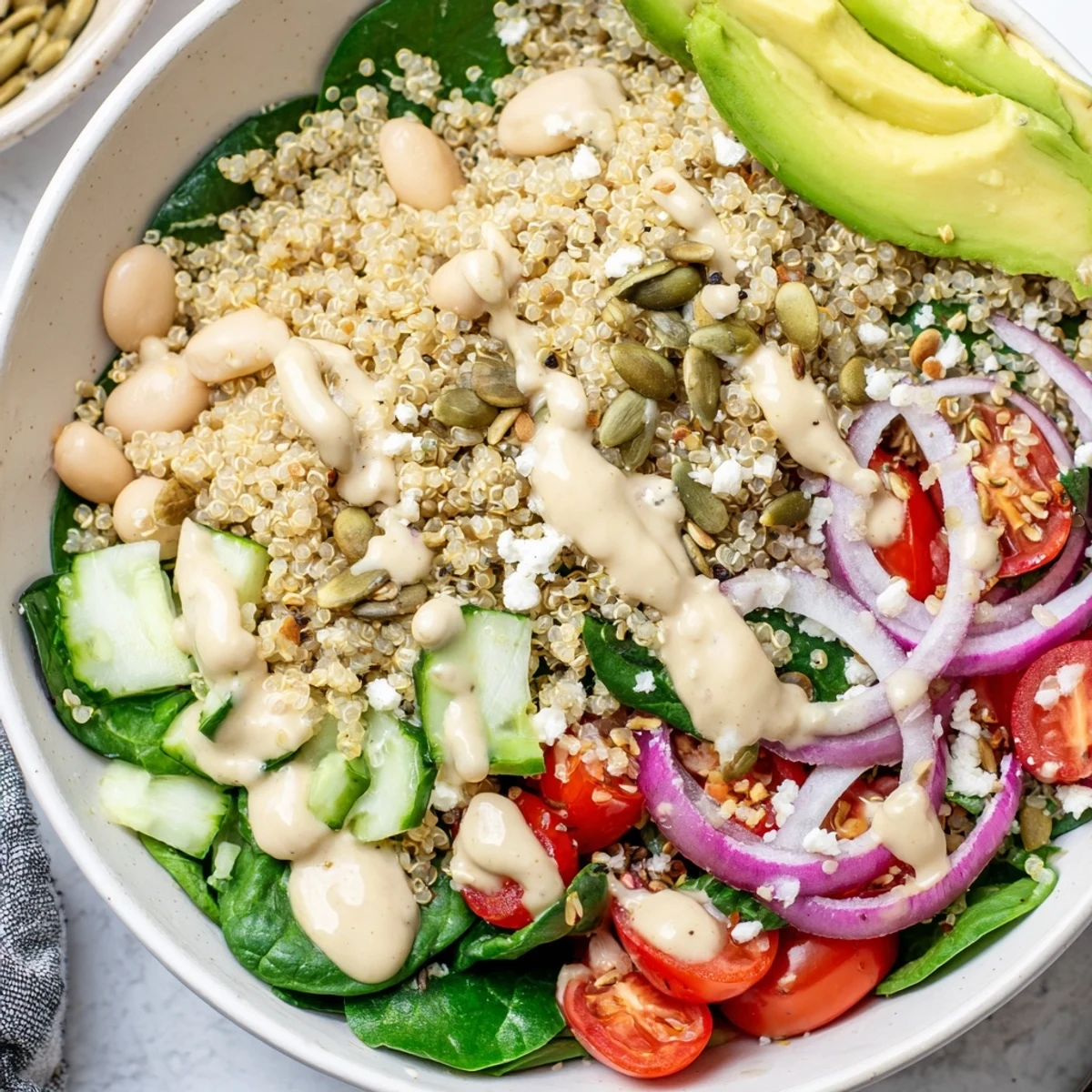 A close-up of the Spinach & White Bean Ultimate Protein Power Bowl with creamy avocado slices and pumpkin seeds.