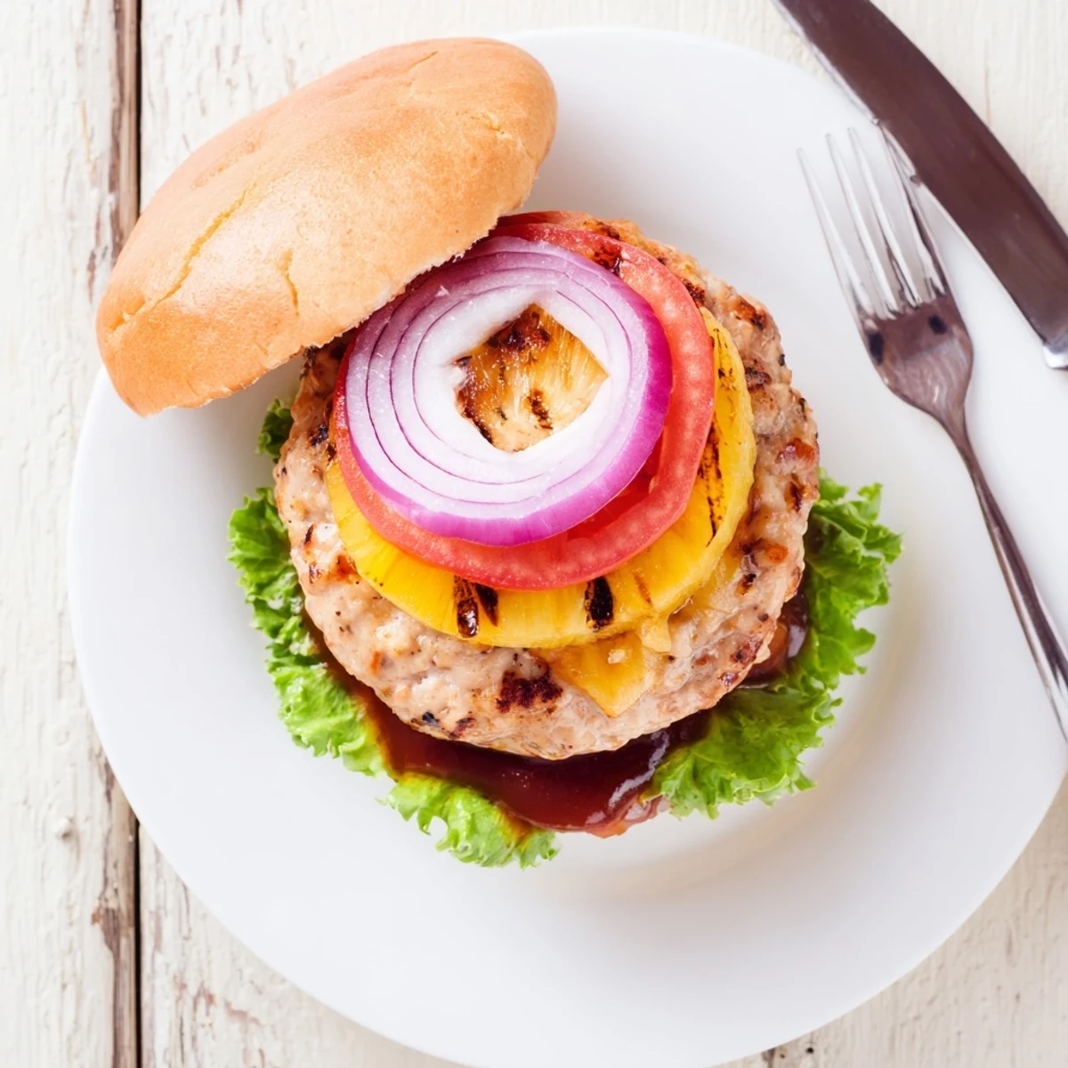 Grilled Hawaiian Pineapple Chicken Burger on toasted bun with melted cheese and barbecue sauce.