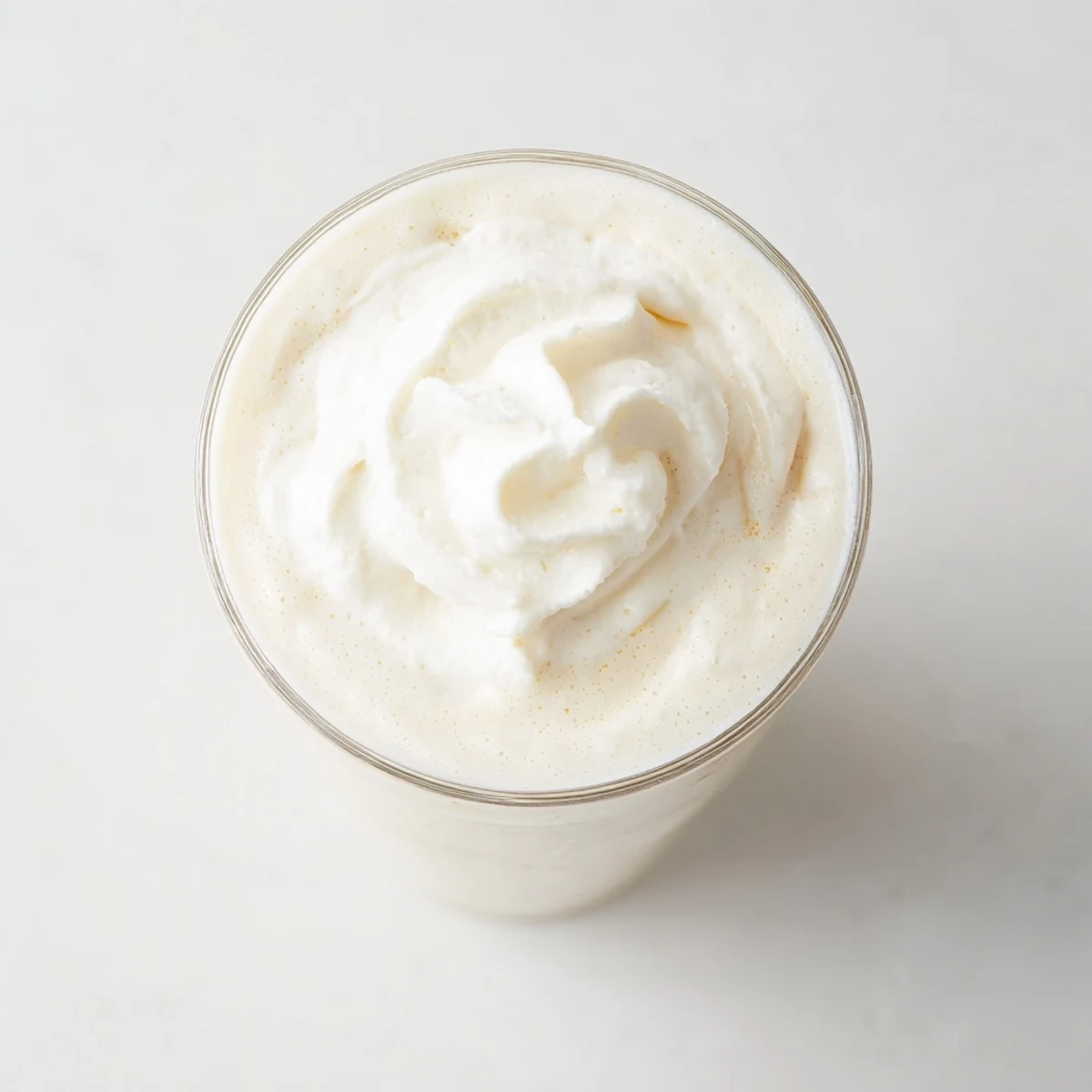 A tall glass of Starbucks Vanilla Bean Frappuccino topped with fluffy whipped cream and a straw.