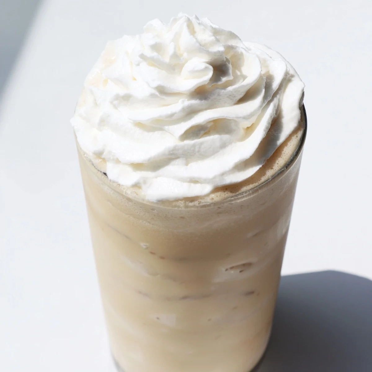 Serving two glasses of Starbucks Vanilla Bean Frappuccino, one with a straw and whipped cream.