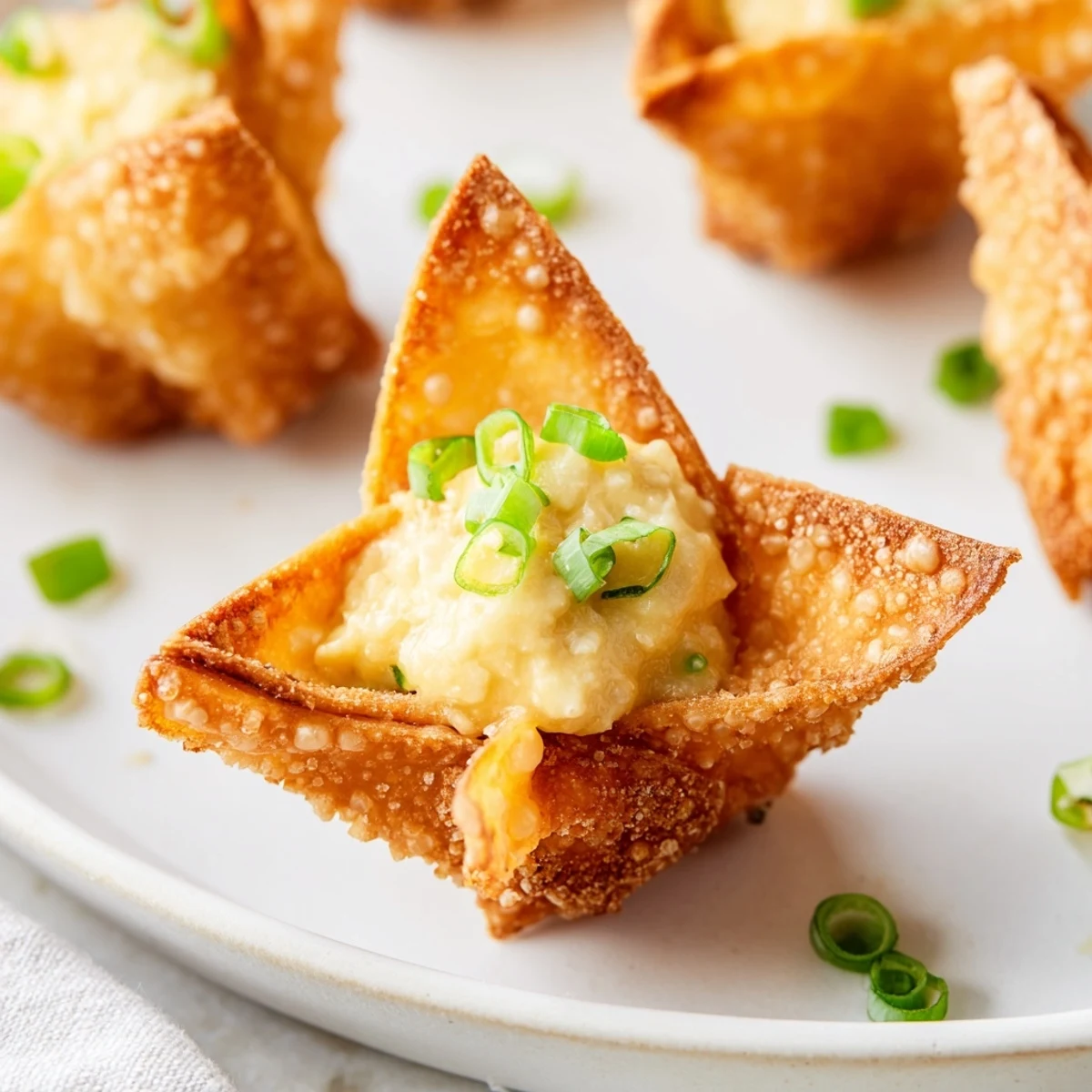 Close-up shot of Crispy Crab Rangoon Bombs showing the golden fried exterior and a cross-section of the savory, creamy crab and cheese filling.