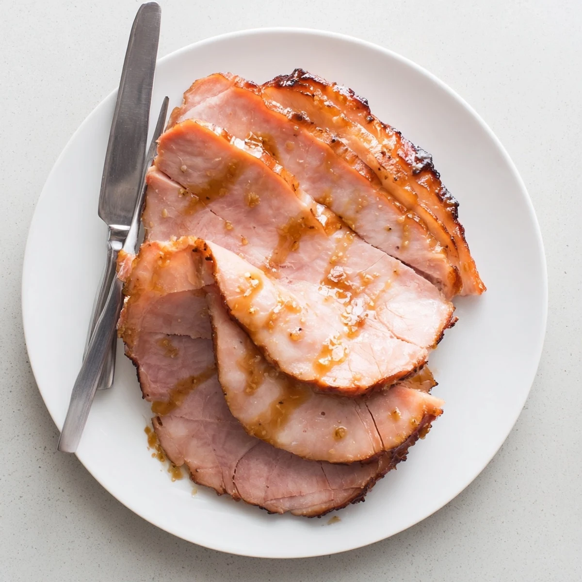 Brown Sugar Mustard Glazed Ham served hot, juicy and tender with a golden sticky glaze on a rustic table.  