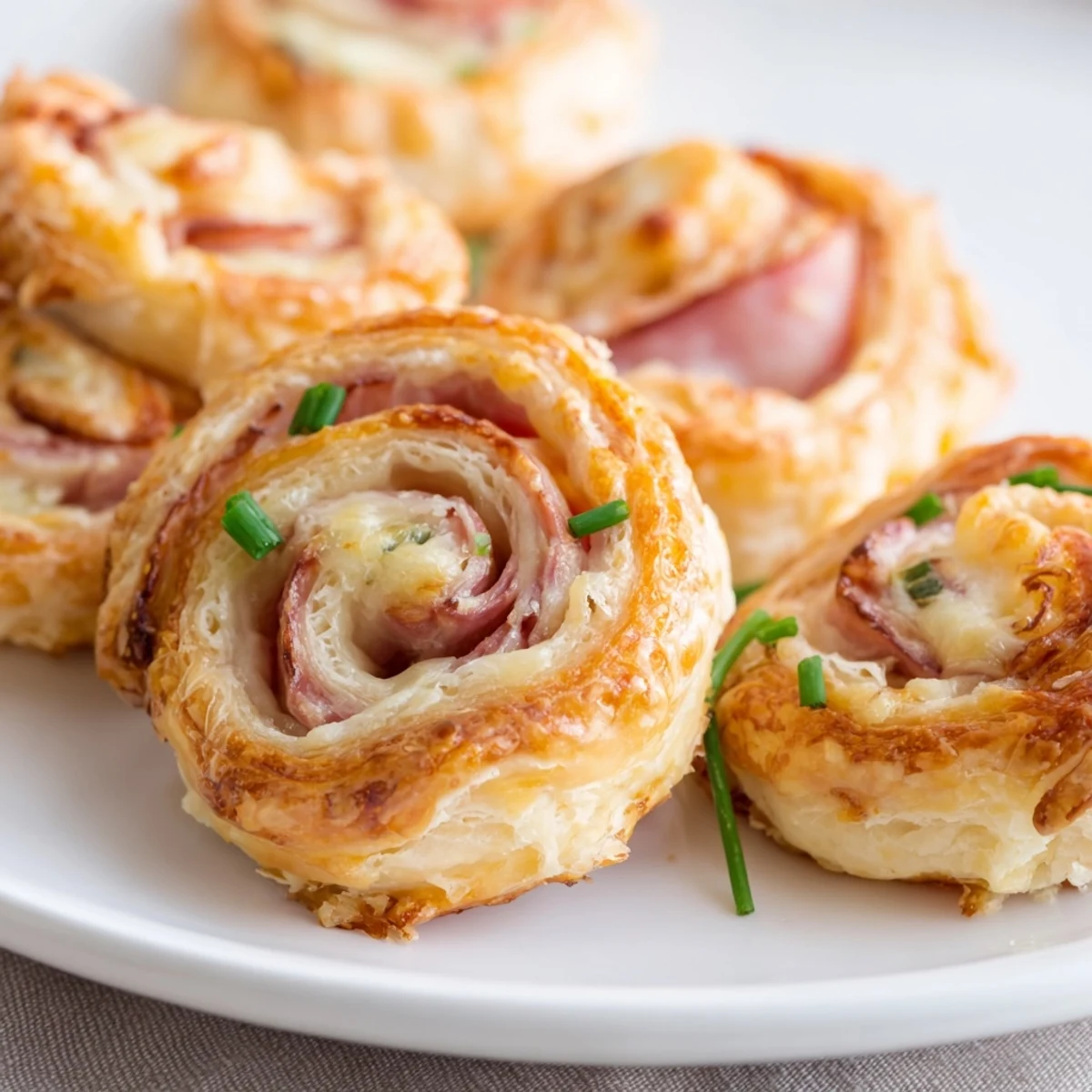 Flaky golden Ham and Cheese Pinwheels with melted cheese and savory ham slices, perfect party appetizers.