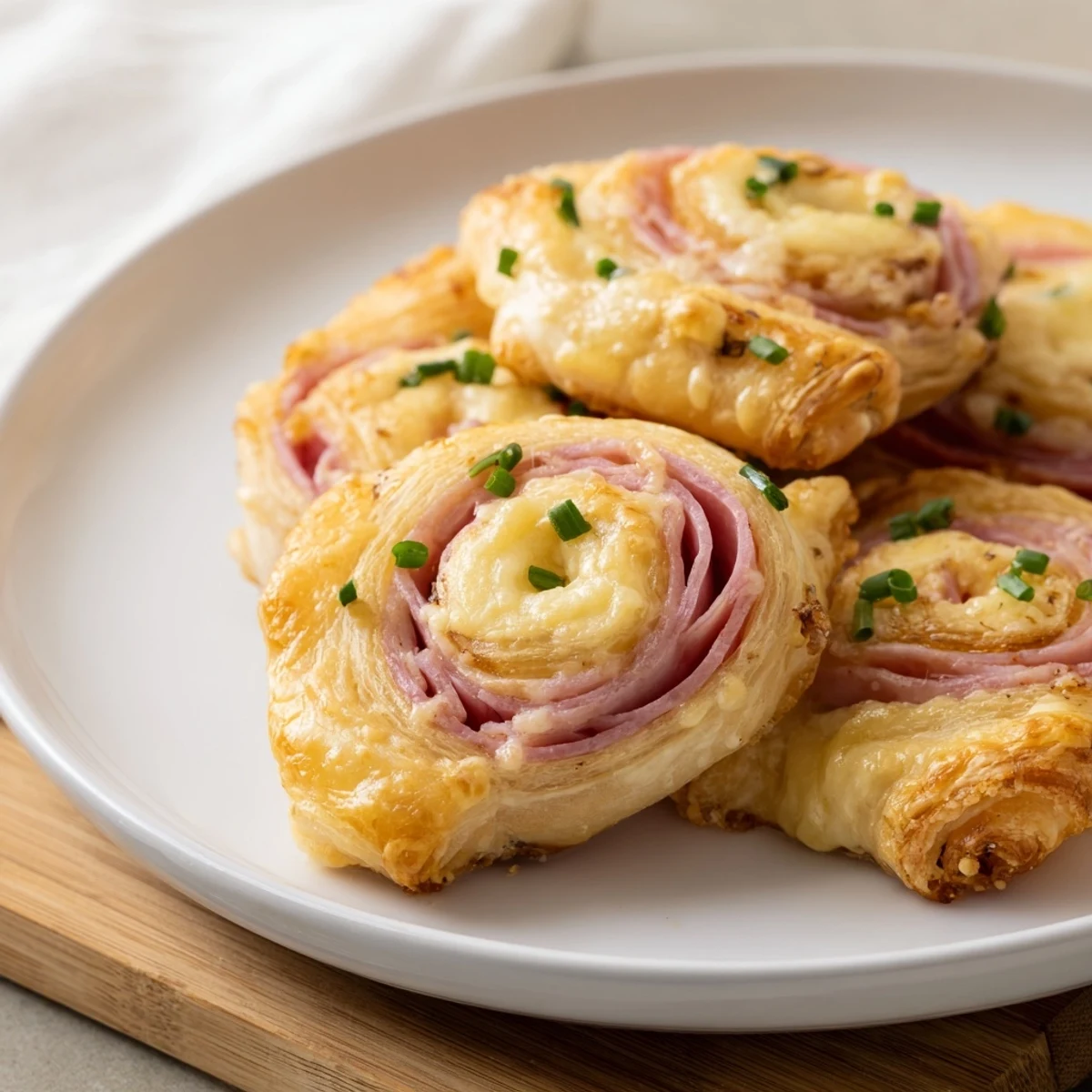 Freshly baked Ham and Cheese Pinwheels on a plate, served warm with a side of tangy dipping sauce.