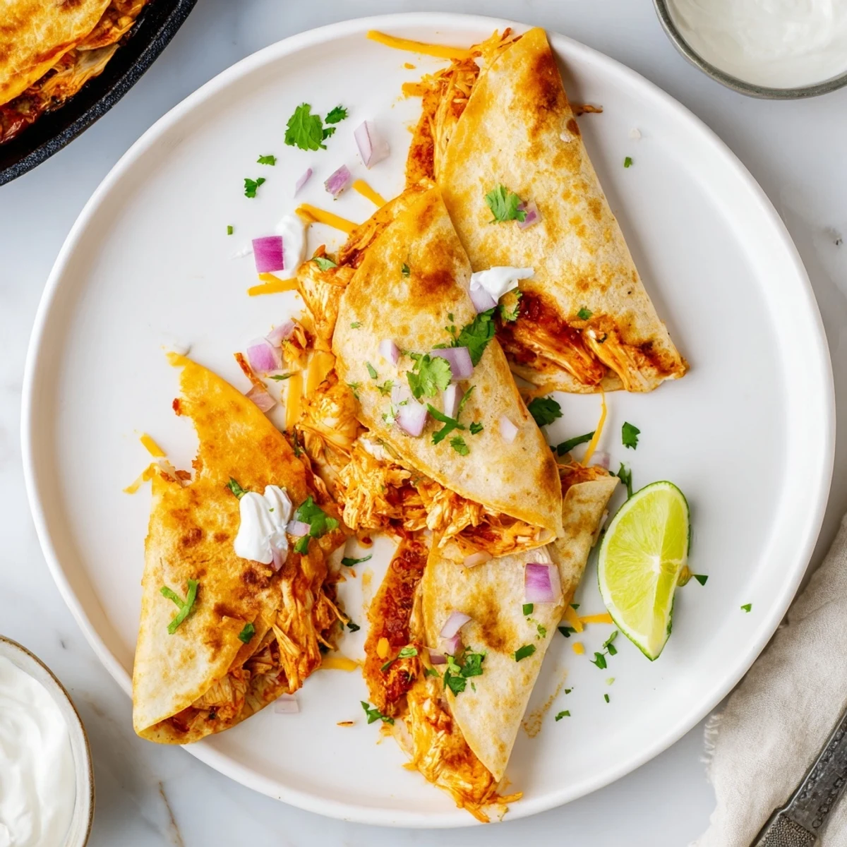 Golden-brown Hot Honey BBQ Chicken Quesadillas sizzling in a skillet, filled with melted cheese and topped with fresh cilantro and lime.