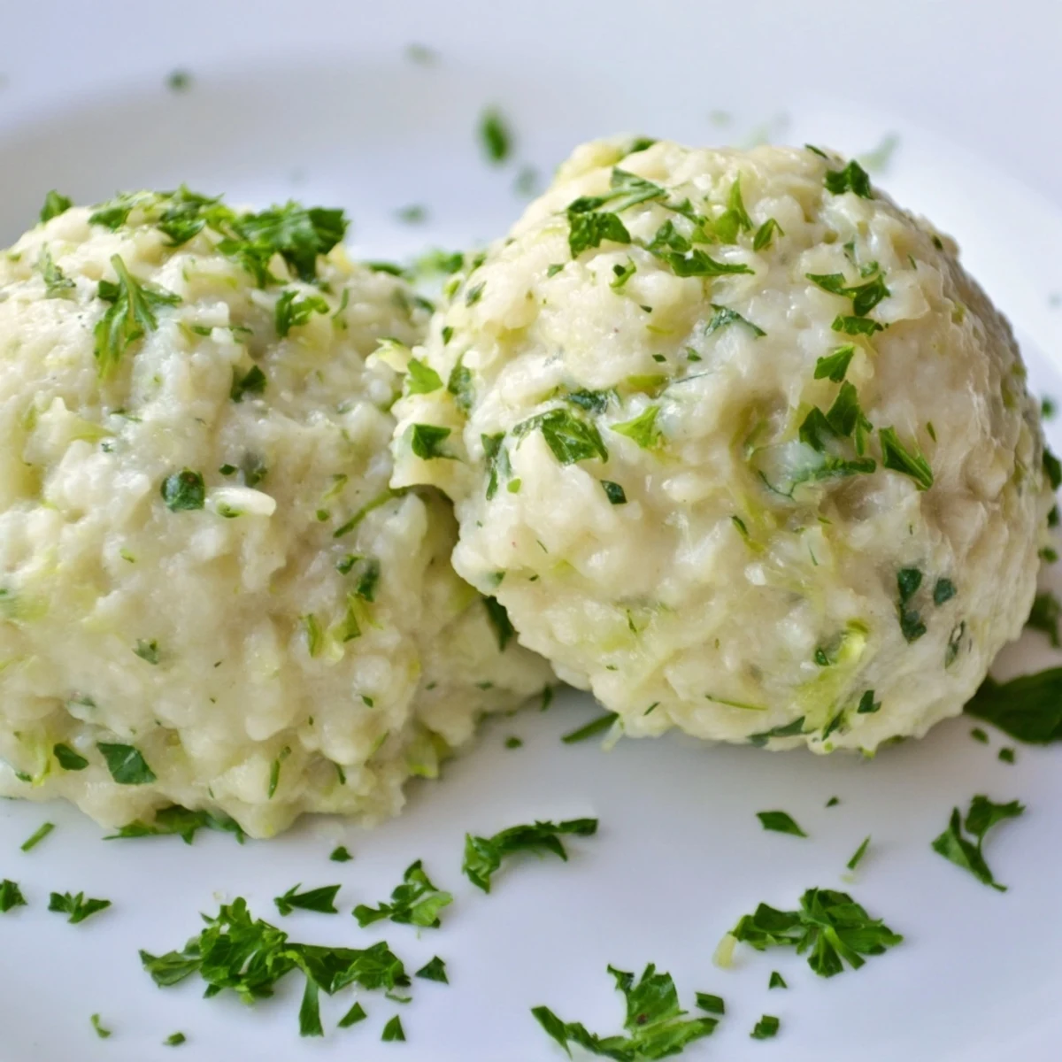 Steaming German Cabbage Dumplings rest in a white bowl next to a fork on a rustic table.  