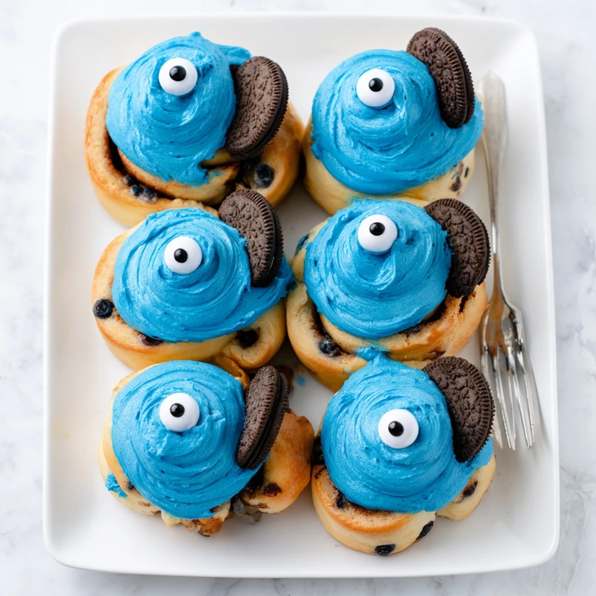 A close-up view of freshly baked Cookie Monster Cinnamon Rolls with gooey cinnamon filling and playful cookie decorations.