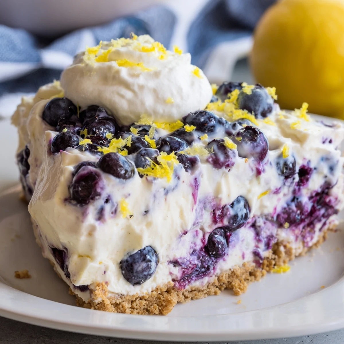 A spoon lifts a bite of No Bake Lemon Blueberry Cream Cake, showing its smooth texture and bright citrus aroma.