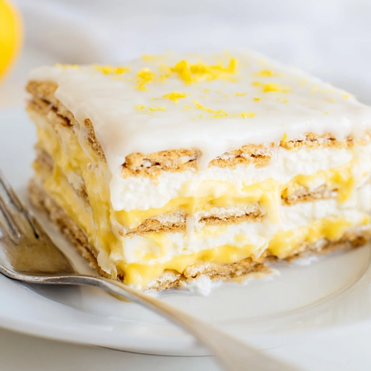 Overhead view of No Bake Lemon Eclair Cake with lemon zest garnish, ideal for easy entertaining and family gatherings.