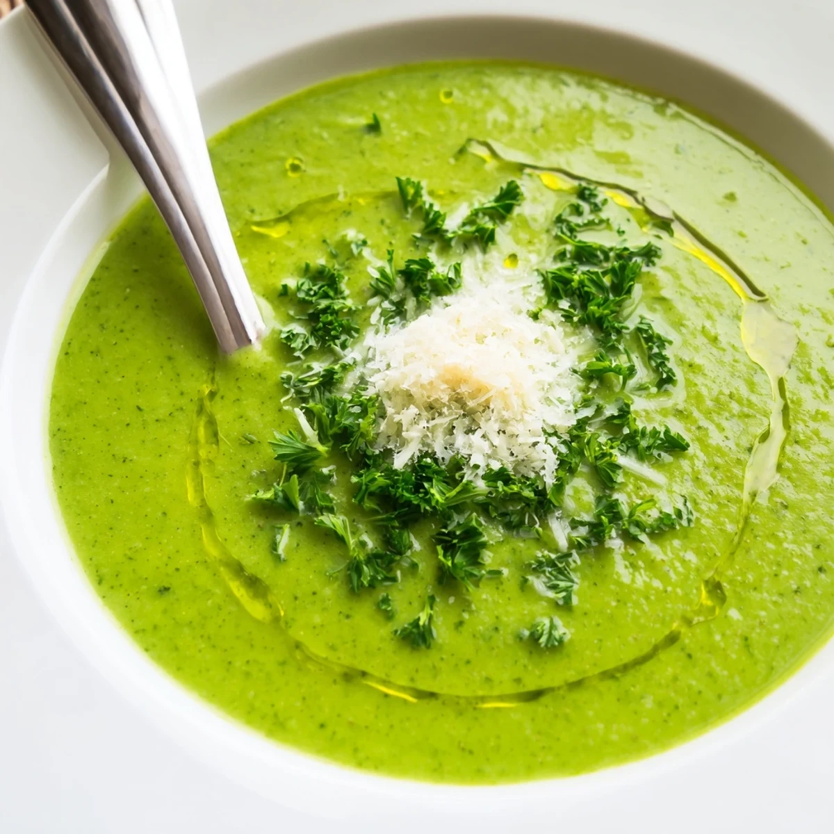 Creamy homemade Italian broccoli soup garnished with grated Parmesan and fresh green herbs in a white bowl