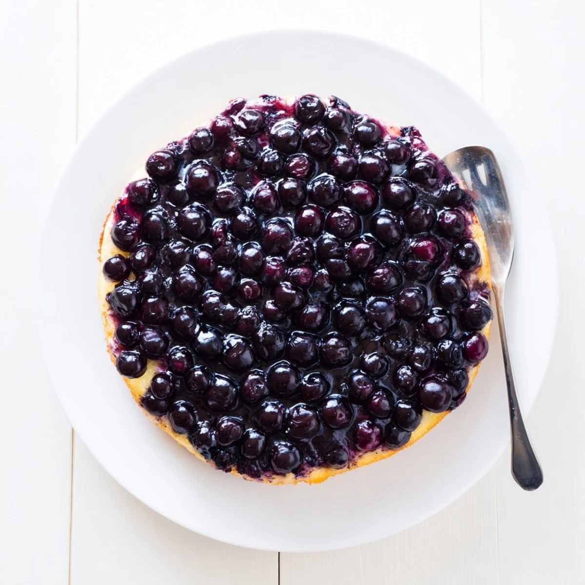 Fresh baked blueberry upside down cake inverted onto serving plate with glistening berry layer