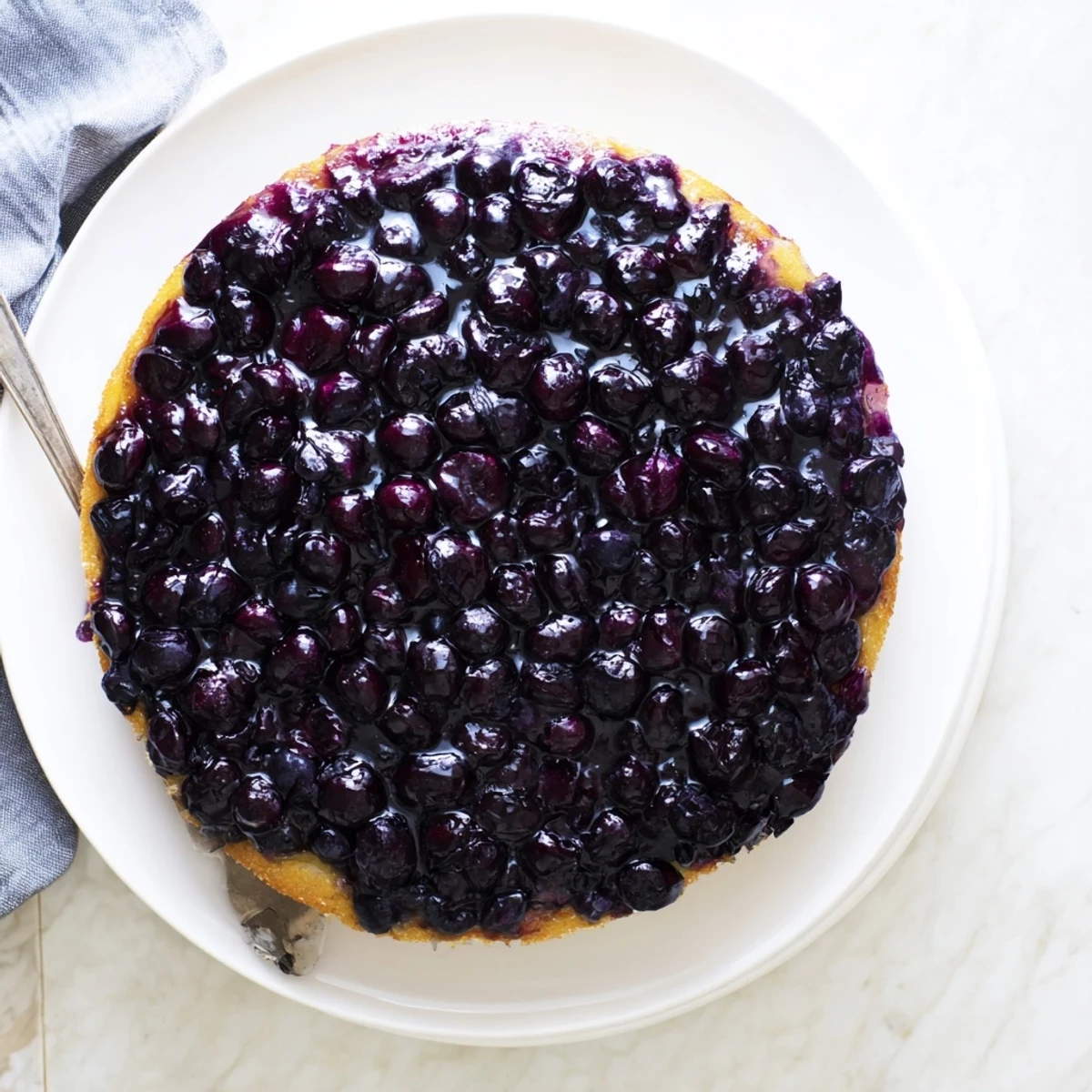 Homemade blueberry upside down cake served warm with whipped cream and whole blueberry garnish