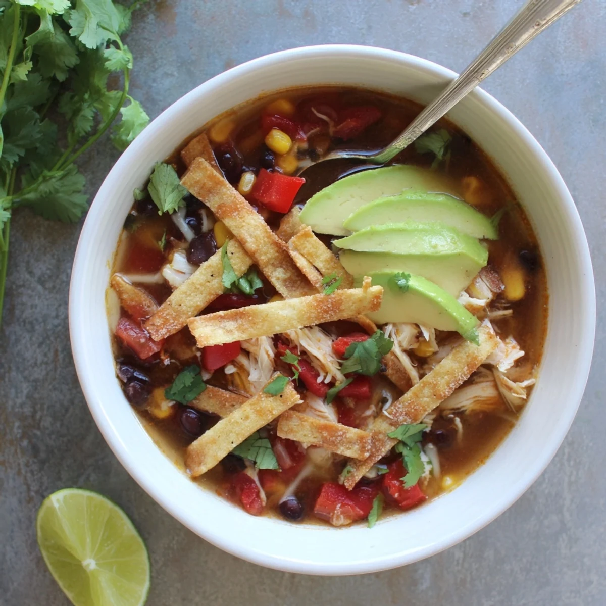 Classic Chicken Tortilla soup bowl topped with golden crispy strips, fresh avocado, and melted cheese