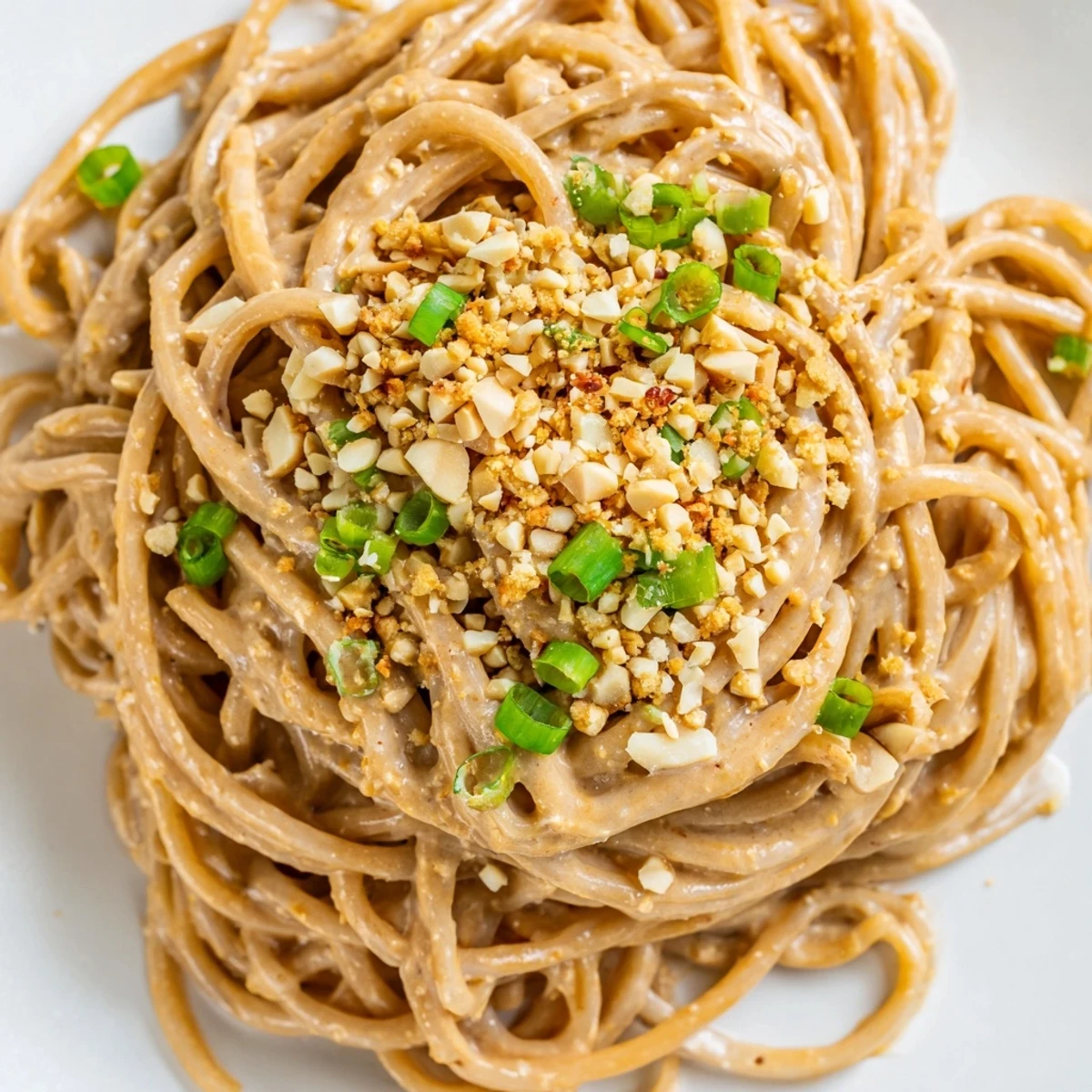 Golden wheat noodles tossed through thick peanut butter sauce drizzled with sriracha and sprinkled with toasted sesame seeds.
