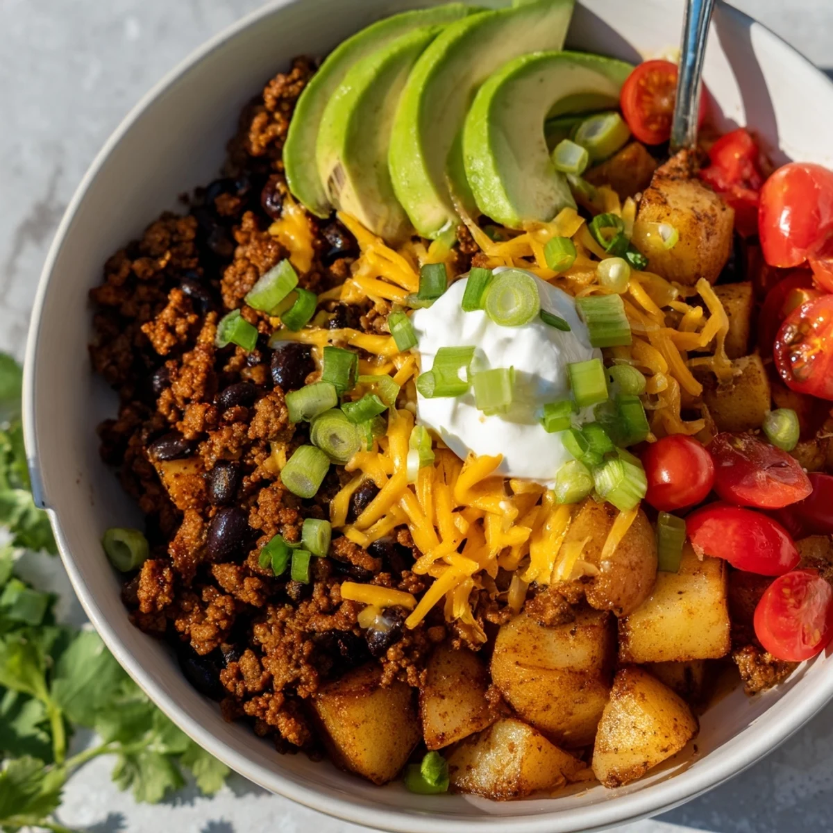 Golden roasted potatoes topped with seasoned ground beef and colorful taco toppings in a ground beef potato taco bowl