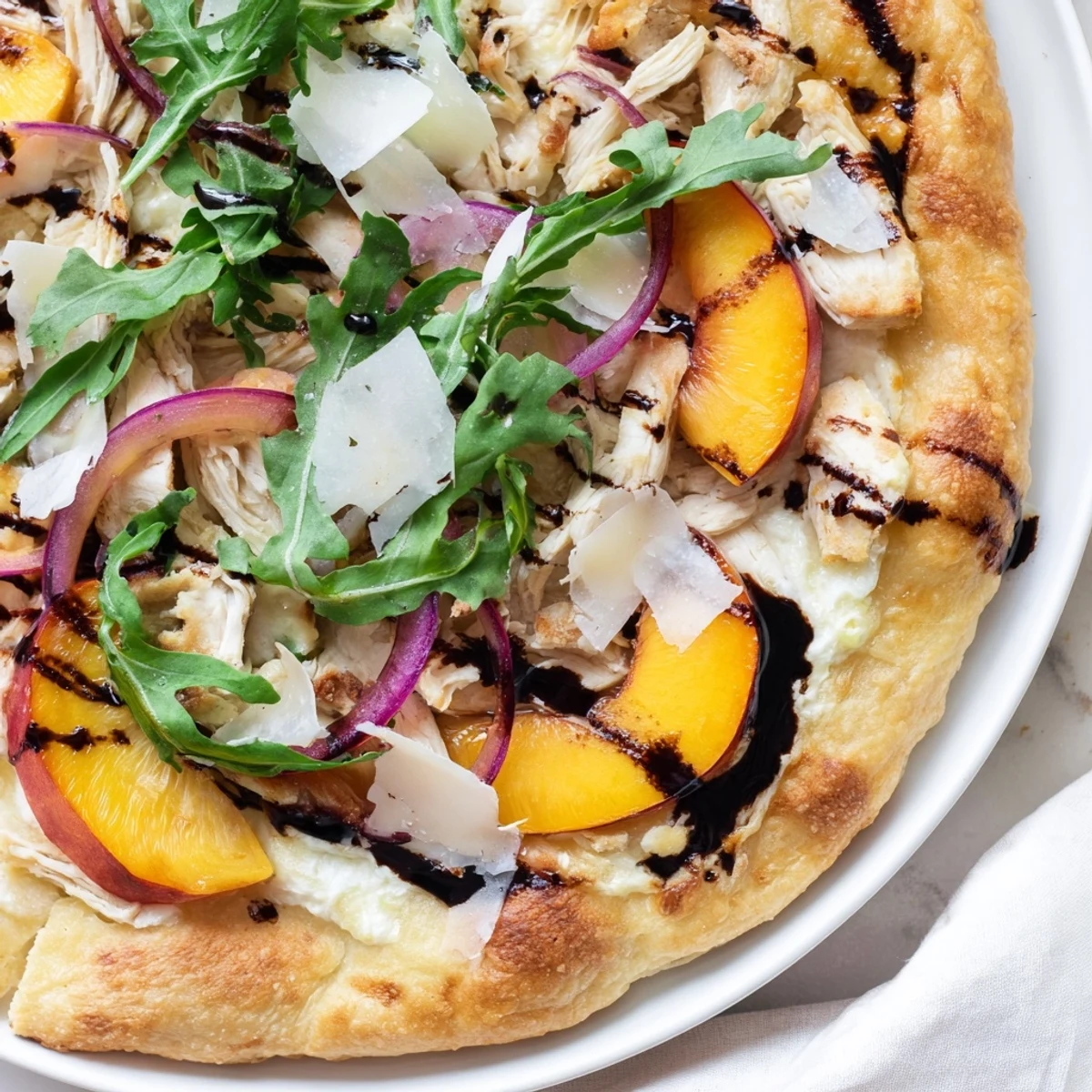 Vibrant chicken peach ricotta pizza with peppery arugula and sweet balsamic finish