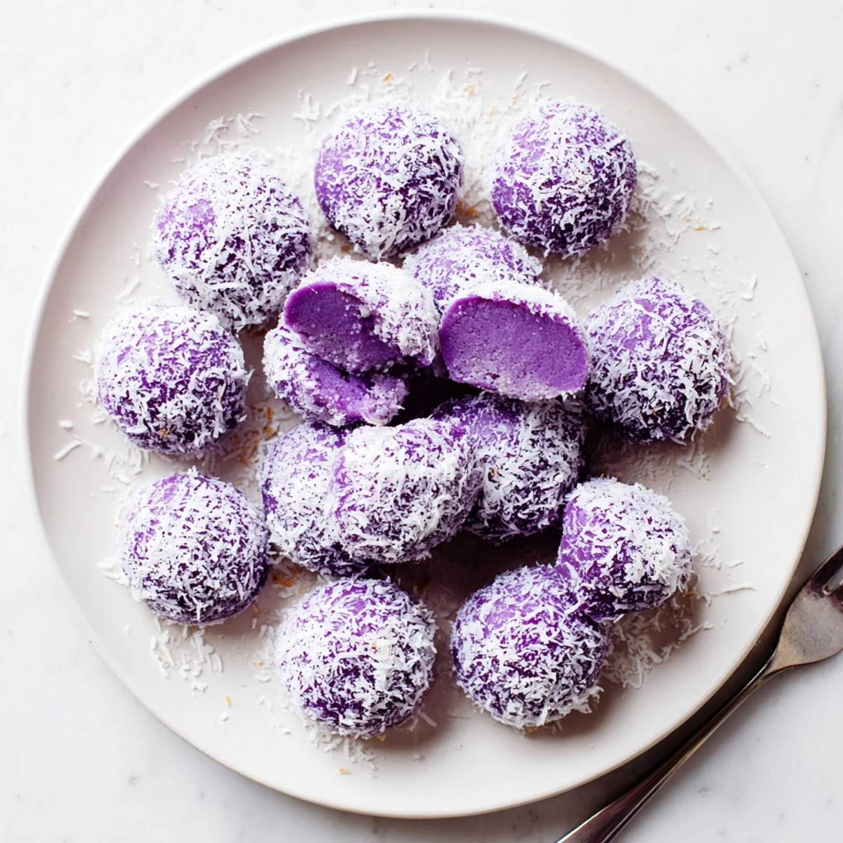 Soft purple Coconut Ube Besito Cookies rolled in white coconut ready for tea time