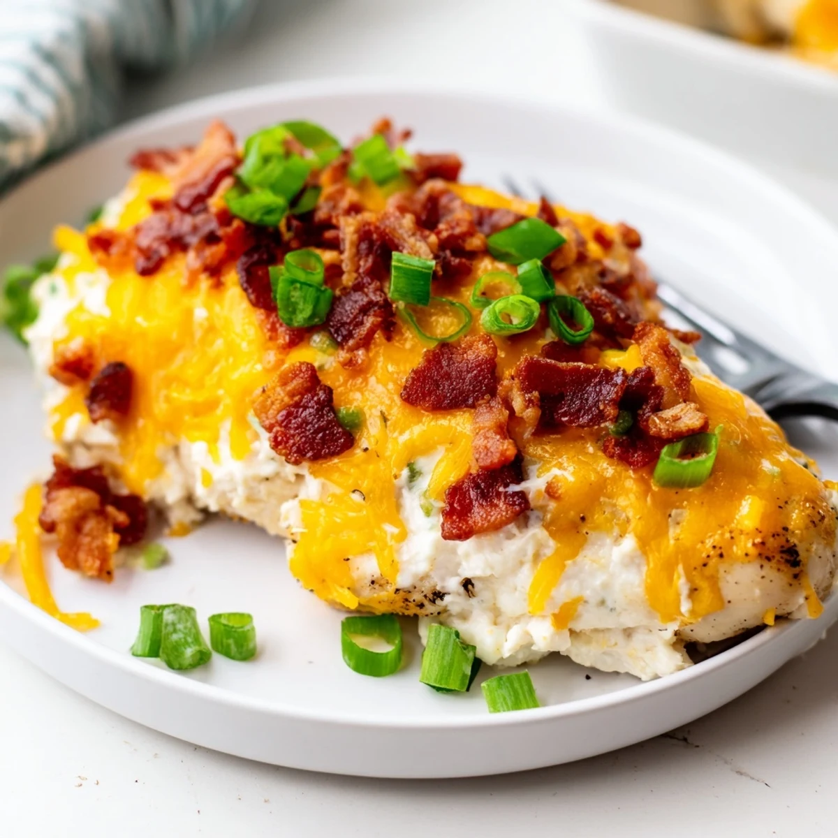 Gluten-free baked crack chicken with green onion garnish served on a rustic wooden cutting board
