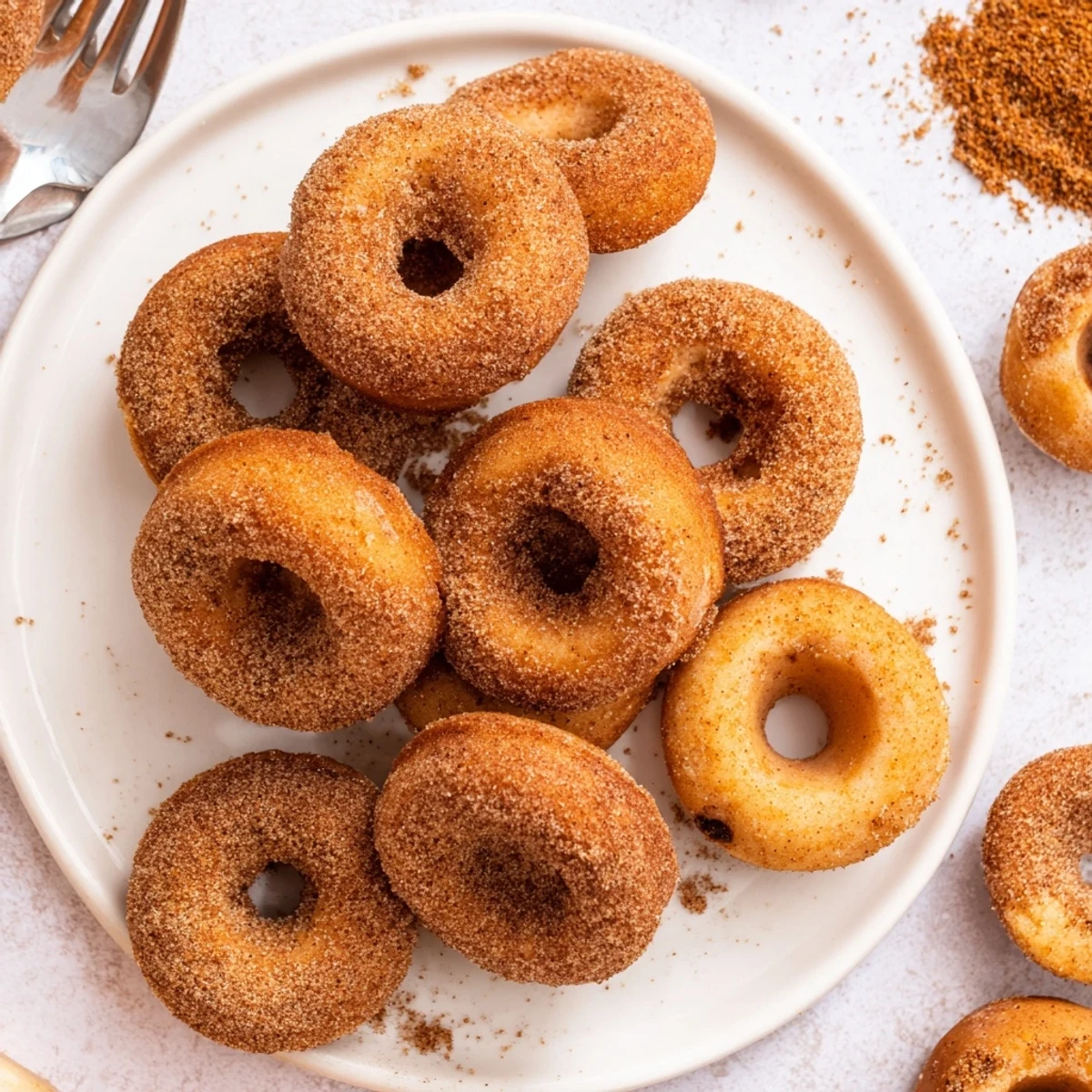 Pillowy biscuit donuts tossed in pumpkin cinnamon sugar resting on paper towels