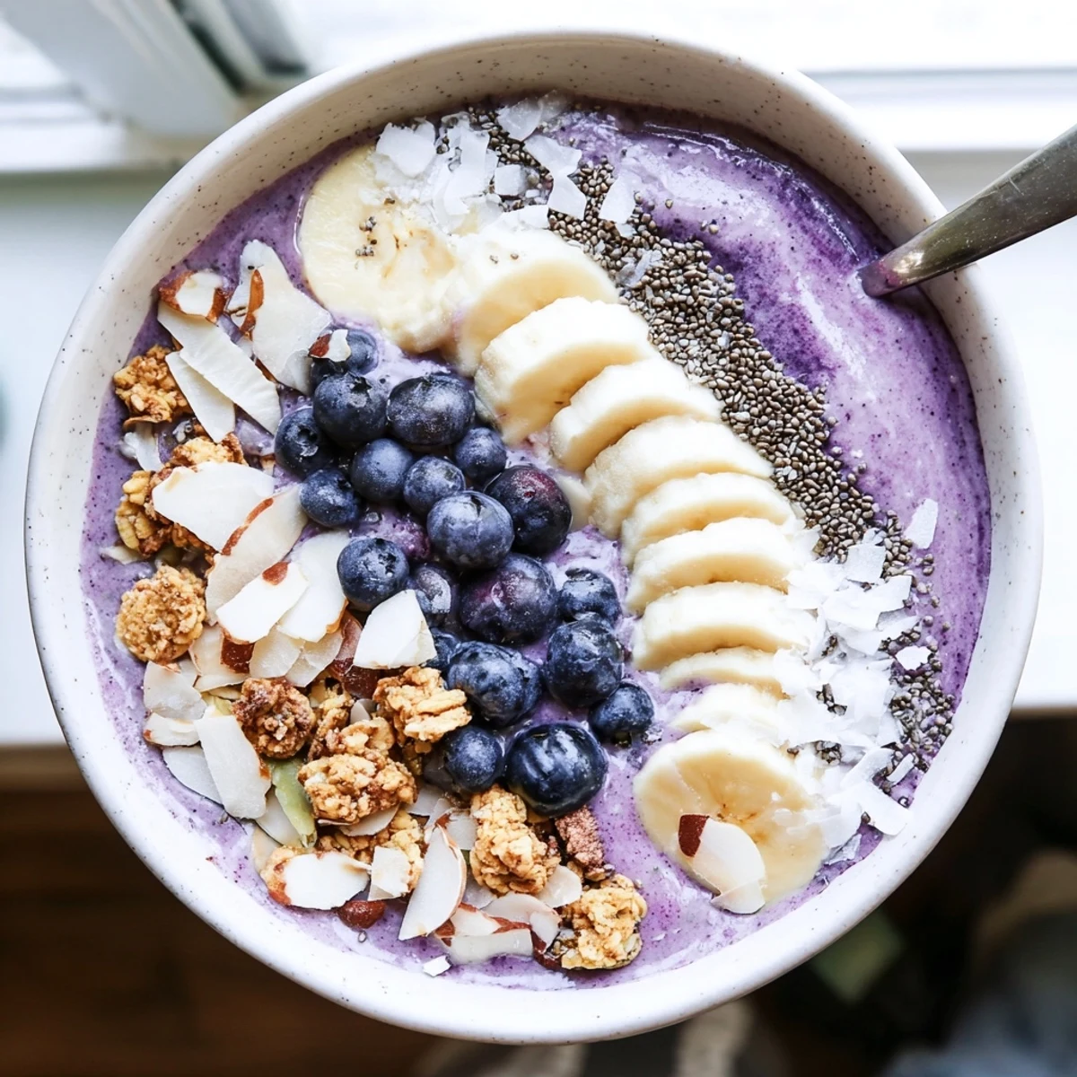 Vibrant blueberry smoothie bowl with Greek yogurt arranged with colorful fruit toppings and almond slices