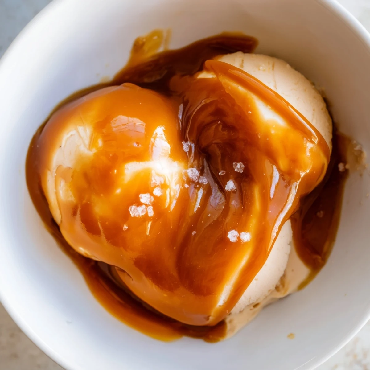 Rich amber easy caramel sauce bubbling in a copper saucepan with wooden spoon stirring