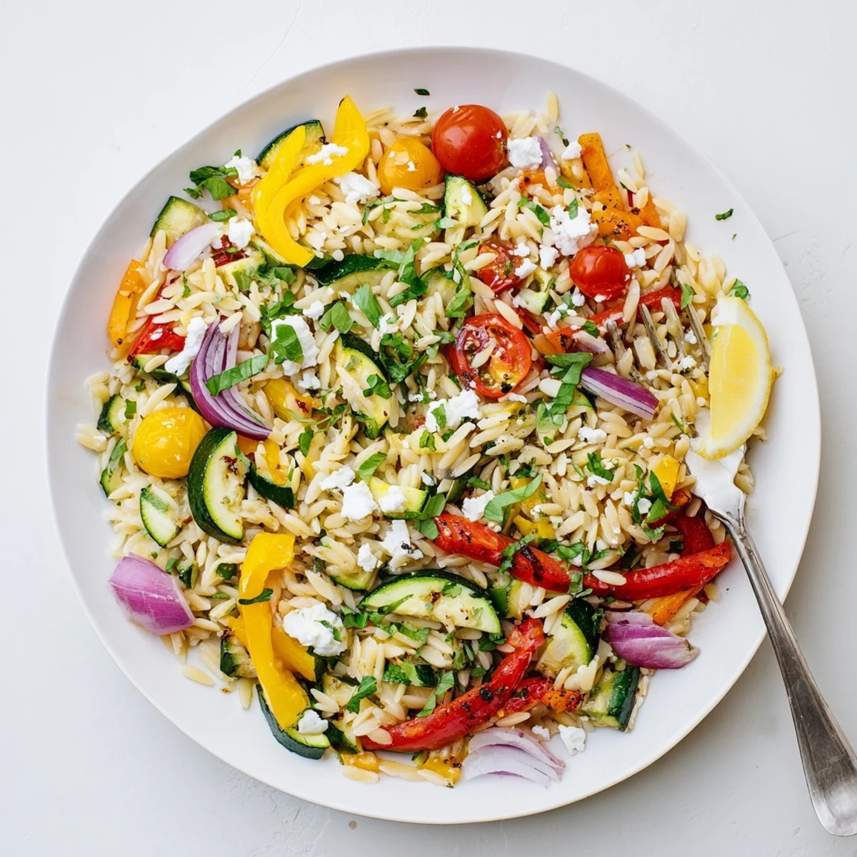 Colorful Mediterranean roasted vegetable orzo with zucchini peppers tomatoes basil and lemon zest