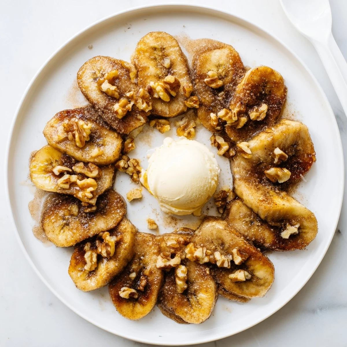 Close up of perfectly browned pan fried cinnamon bananas in a skillet with melted butter and visible spice dusting