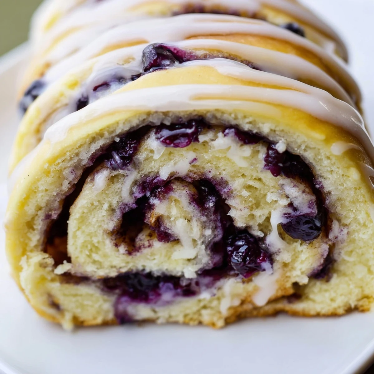 Soft fluffy pastry spirals topped with creamy lemon icing and bursting berries