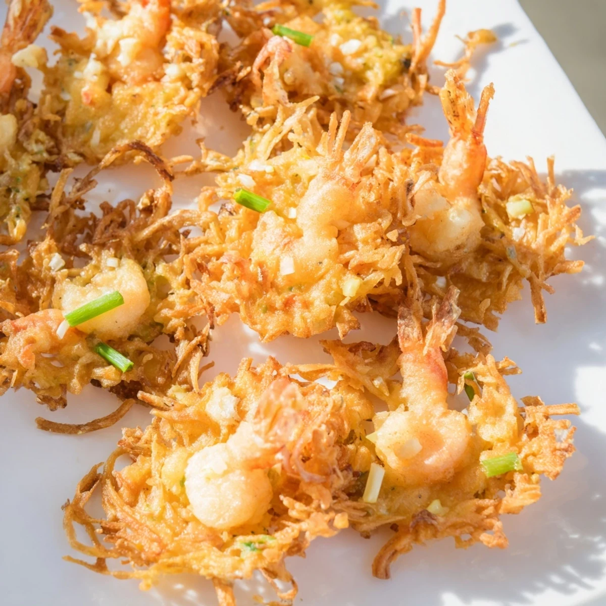 Golden crispy Ukoy Filipino shrimp fritters topped with vibrant orange carrots and bean sprouts