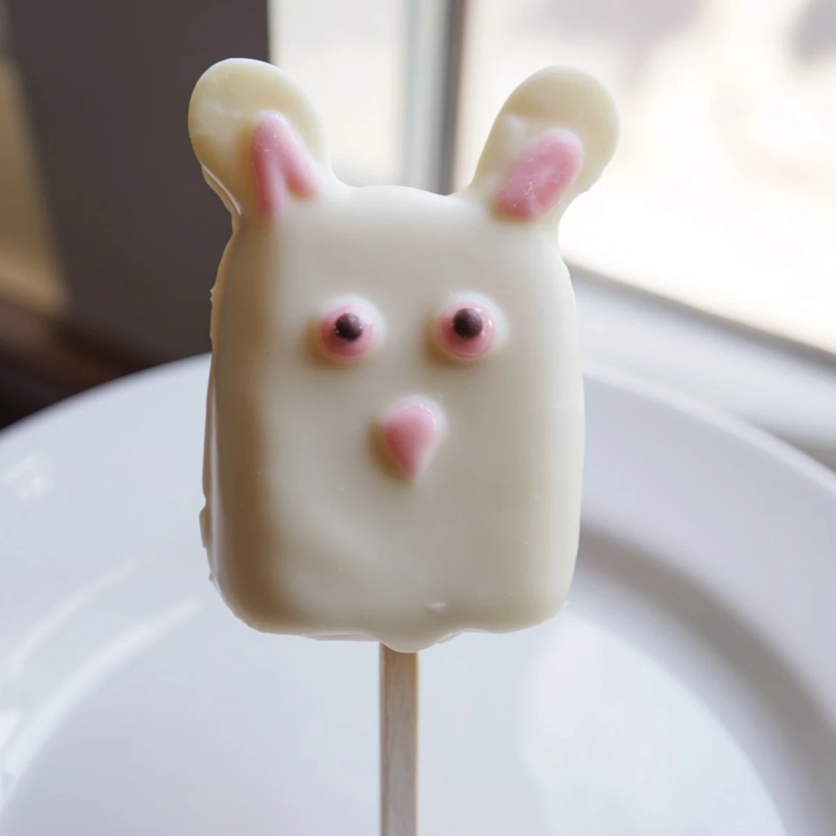 Adorable white chocolate bunny cakesicles with candy eyes and pink fondant ears on sticks