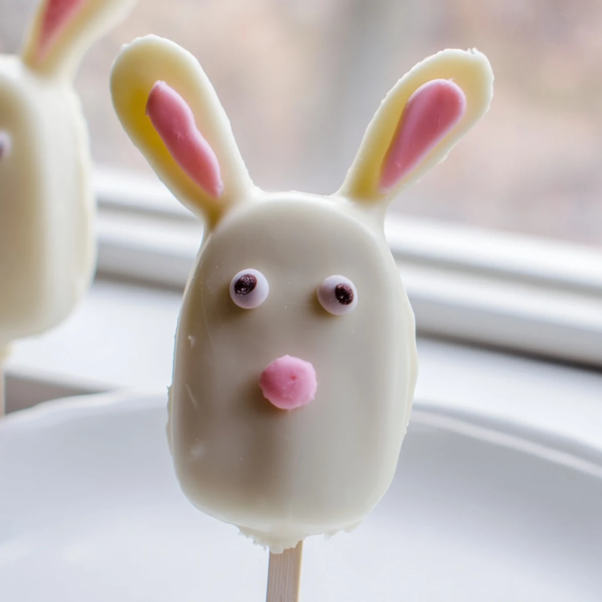 Creamy white chocolate bunny cakesicles decorated with colorful sprinkles for festive Easter treats