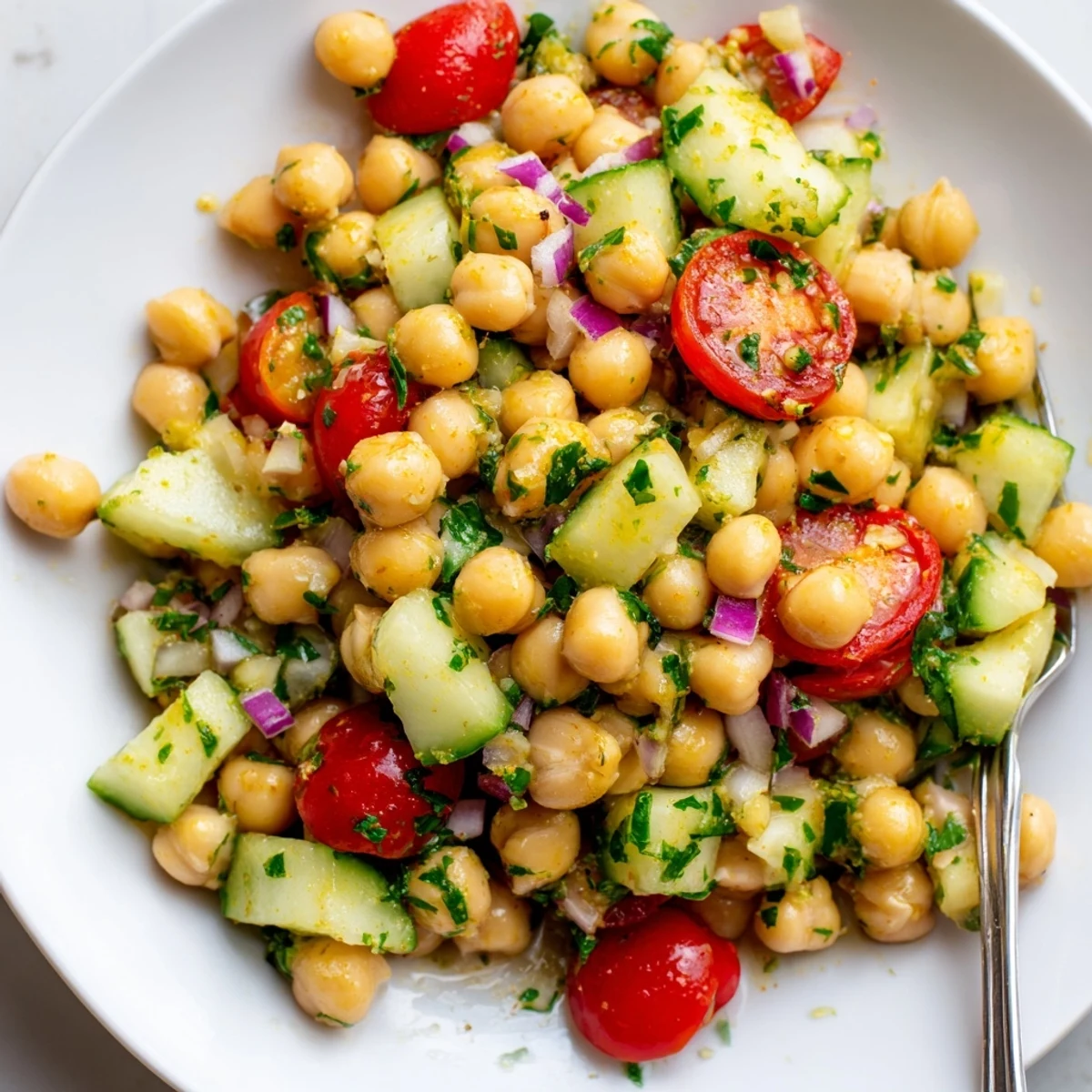 A vibrant chickpea cucumber salad topped with cherry tomatoes and herby lemon dressing